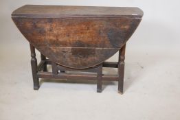 An C18th oak drop leaf table raised on turned supports with shaped block ends, 41" x 15" x 26"