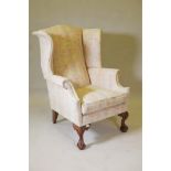 A wingback armchair on carved cabriole supports with ball and claw feet, upholstered in a floral
