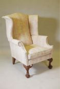 A wingback armchair on carved cabriole supports with ball and claw feet, upholstered in a floral