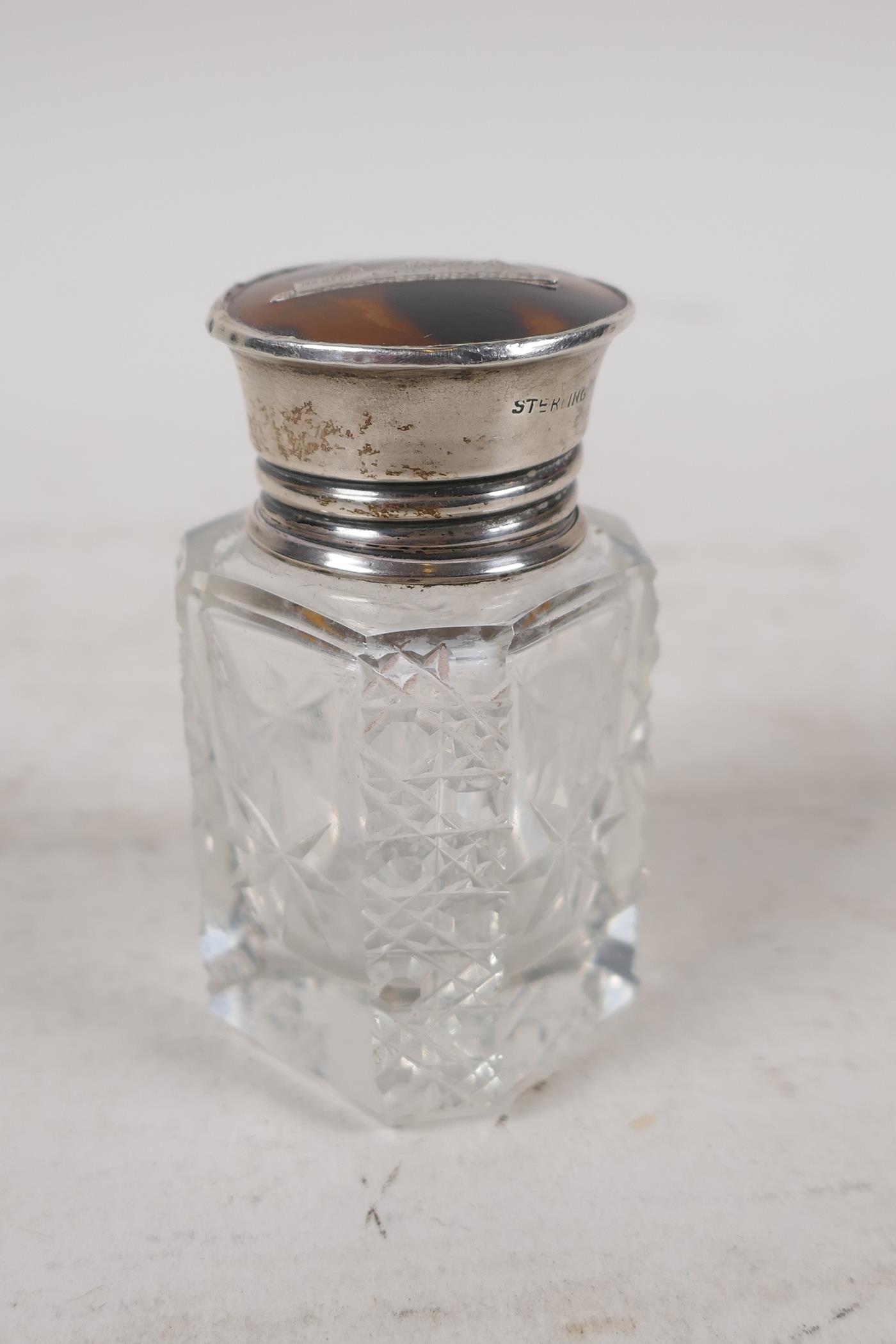 A cut glass scent bottle with a sterling silver and tortoiseshell cup, the lid with inset silver