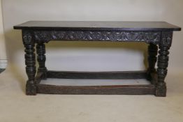 A C17th oak refectory table with carved frieze, raised on turned supports united by stretchers,