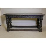 A C17th oak refectory table with carved frieze, raised on turned supports united by stretchers,