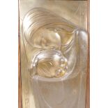 A bas relief metal plaque of a mother and child, signed M. Registrado M.F., 10" x 19", framed