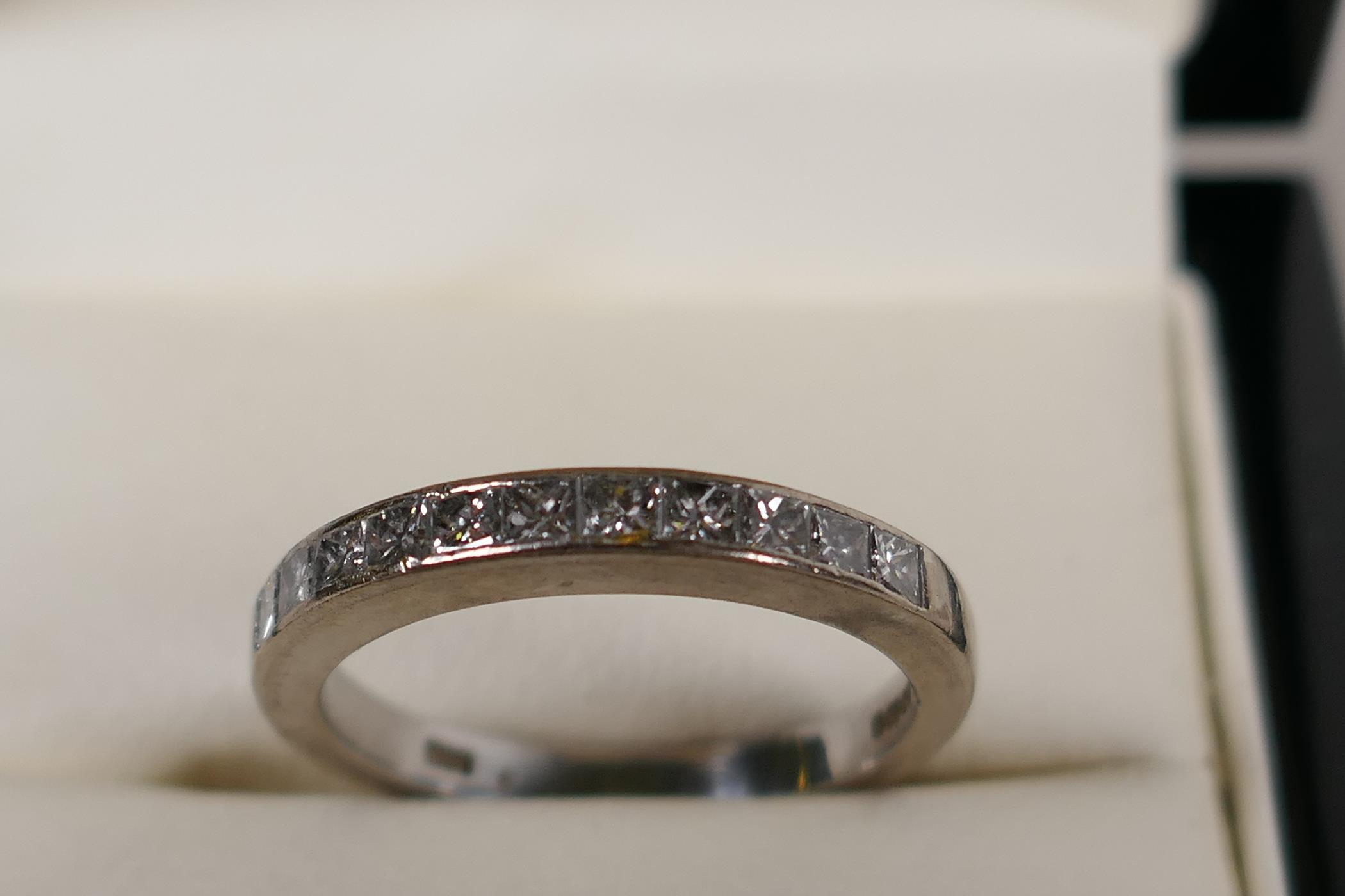A hallmarked 18ct white gold half eternity ring, set with eleven princess cut diamonds, .5ct
