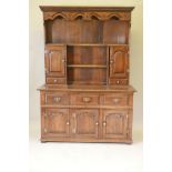 An oak dresser and plate rack with three drawers over three doors to the base, the upper section