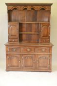 An oak dresser and plate rack with three drawers over three doors to the base, the upper section