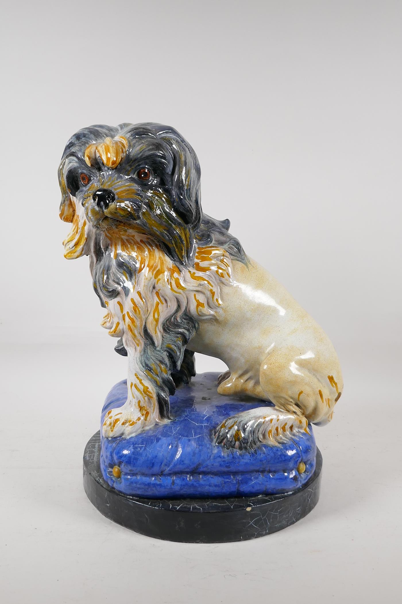 A Majolica pottery dog on a blue pillow, 16" high