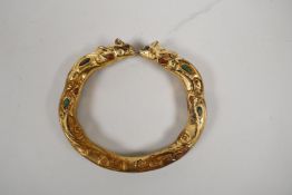 A Chinese gilt metal bangle with rat head decoration and inset with turquoise and coral, 3" diameter