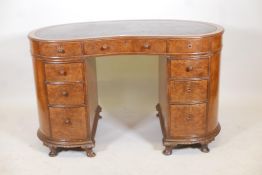 A late C19th/early C20th walnut kidney shaped pedestal desk with leather tooled top and nine drawers