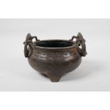 A Chinese bronze two handled censer raised on tripod supports, with dragon decoration, six character