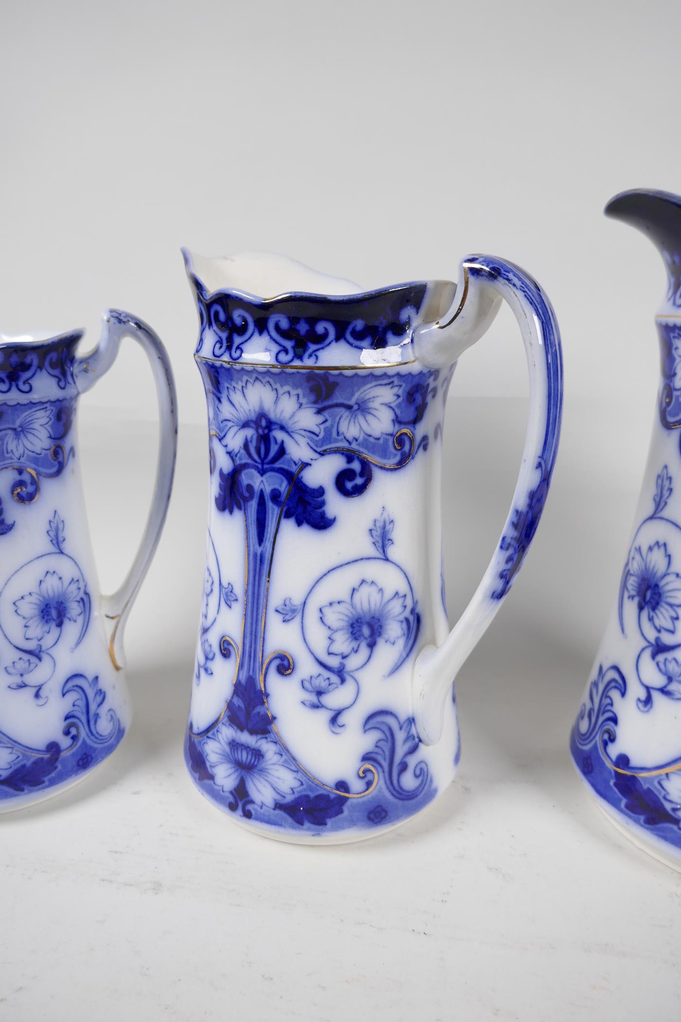 A set of three graduated Art Nouveau blue and white pottery jugs with gilt embellishments from F & - Image 2 of 3