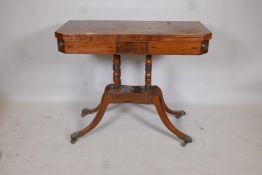 A Regency inlaid figured mahogany card table with canted corners raised on ring turned columns,