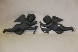 A pair of painted cast iron wall plaques in the form of cherubs, A/F, 28" long