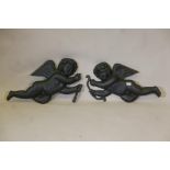 A pair of painted cast iron wall plaques in the form of cherubs, A/F, 28" long