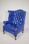A Georgian style blue leather buttoned wing back armchair, 42" high