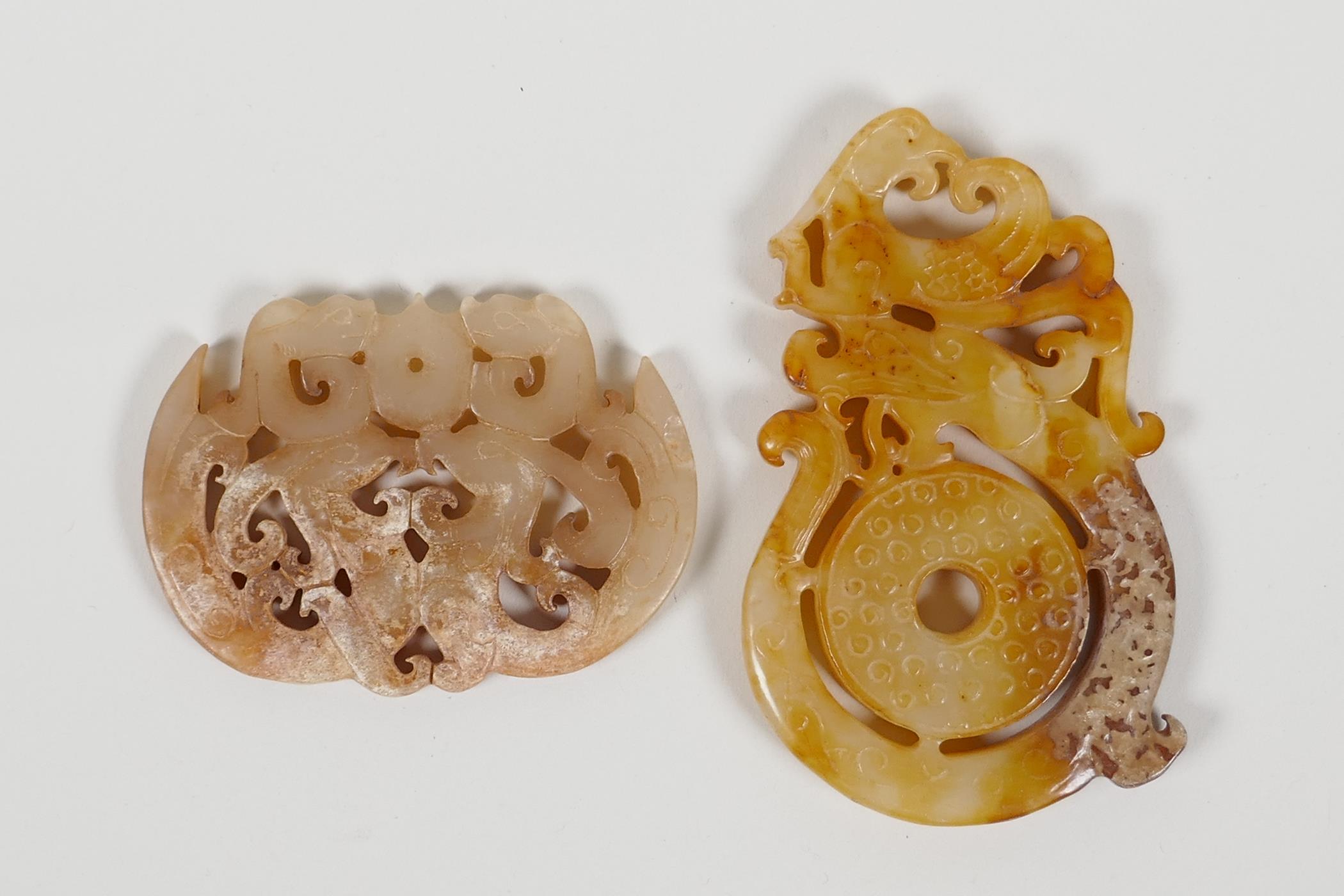 A Chinese carved and pierced hardstone pendant with dragon and phoenix decoration, and another