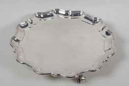 A hallmarked silver serving tray with gadrooned rim, on three cast scroll supports, hallmarked