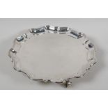 A hallmarked silver serving tray with gadrooned rim, on three cast scroll supports, hallmarked