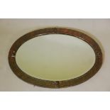 An Arts & Crafts hammered copper wall mirror with decorative mounts and bevelled glass, 35" x 24"