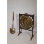 An antique brass charger mounted in an oak screen frame with repousse decoration of a husband and