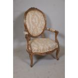 An early C19th walnut show frame open arm spoon back chair with carved back and front rail, raised