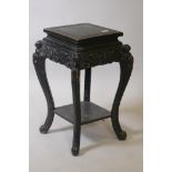 A Chinese two tier ebonised wood stand, with carved bat frieze, raised on scrolled shaped