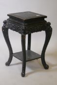 A Chinese two tier ebonised wood stand, with carved bat frieze, raised on scrolled shaped