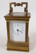 A Swiss made carriage clock in brass case with reeded columns, white enamel dial and Roman numerals,
