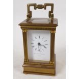 A Swiss made carriage clock in brass case with reeded columns, white enamel dial and Roman numerals,