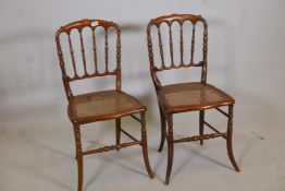 A pair of stained beechwood rout chairs with shaped spindle backs, caned seats, raised on sabre