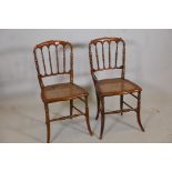 A pair of stained beechwood rout chairs with shaped spindle backs, caned seats, raised on sabre