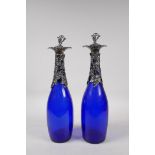 A pair of blue glass decanters with silver plate fruiting vine mounts and stoppers, 13" high