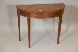 A Regency inlaid mahogany demilune card table with a marquetry top, raised on square tapering