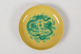 A Chinese yellow ground porcelain saucer decorated with green incised dragons, six character mark to