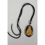 An oriental black glass pendant with carved and gilt Quan Yin decoration, A/F, chips, 1½" x 2"