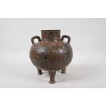 A Chinese bronze two handled vase raised on tripod supports, with raised and engraved archaic