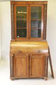 A Victorian cylinder top bureau bookcase, the upper section with two glazed doors and carved