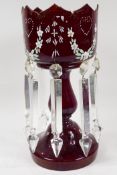 A Victorian ruby glass table lustre with crystal drops, and  painted with flowers, one drop missing,