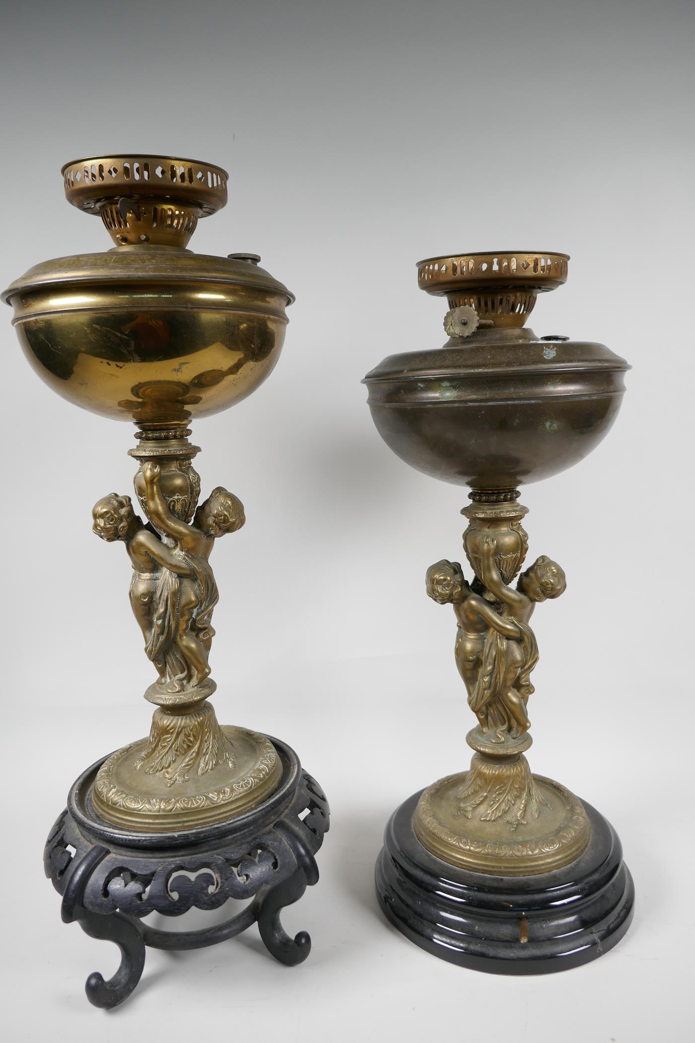 Two table lamps, the central bronze columns cast as two cherubs supporting an urn, with brass oil