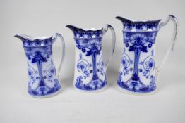 A set of three graduated Art Nouveau blue and white pottery jugs with gilt embellishments from F &
