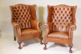 A pair of button back brown leather wing armchairs, on carved ball and claw feet, 41" high