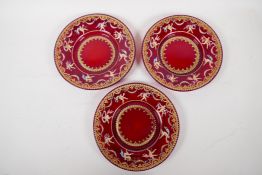 Three Venetian ruby glass plates enamelled with Pompeian figures, within a gilt and floral border,