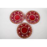 Three Venetian ruby glass plates enamelled with Pompeian figures, within a gilt and floral border,