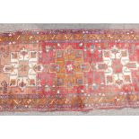 A Persian red ground full pile hand woven wood runner with a cream and amber medallion design, A/F