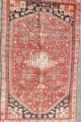 A Persian Heriz hand woven red and black ground wool rug with an all over design and cream border,