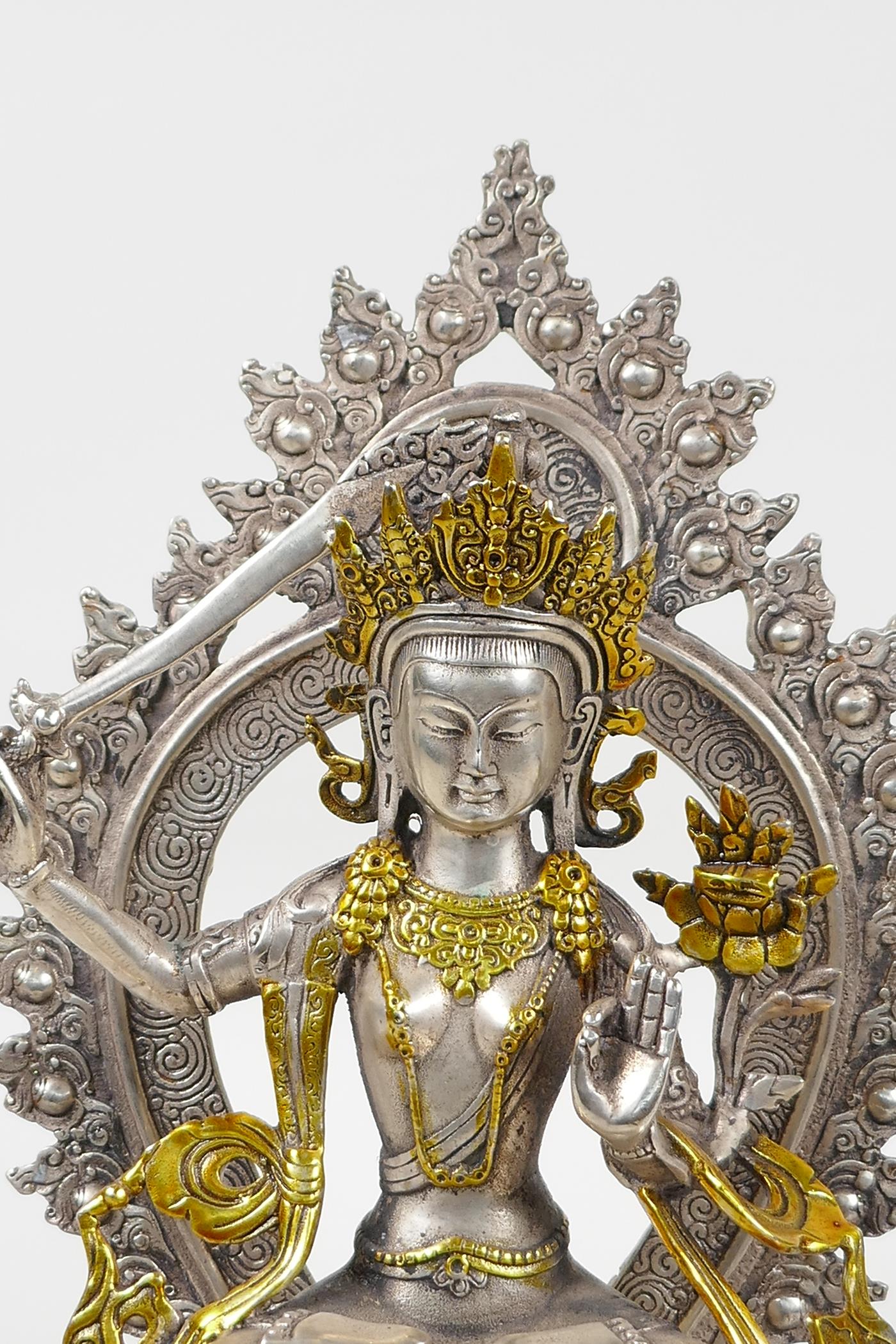 A Sino Tibetan white metal figure of a seated deity carrying a sword with gilt highlights, double - Image 2 of 5