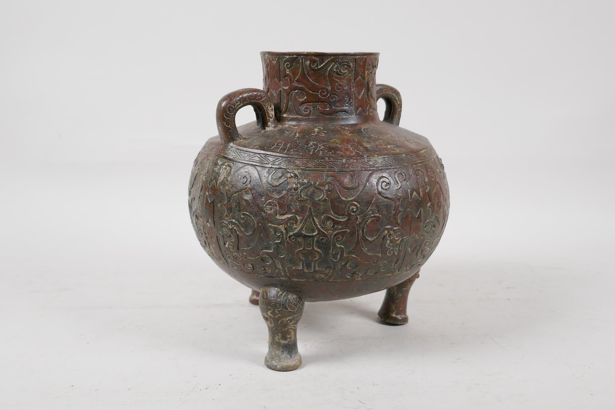 A Chinese bronze two handled vase raised on tripod supports, with raised and engraved archaic - Image 3 of 7