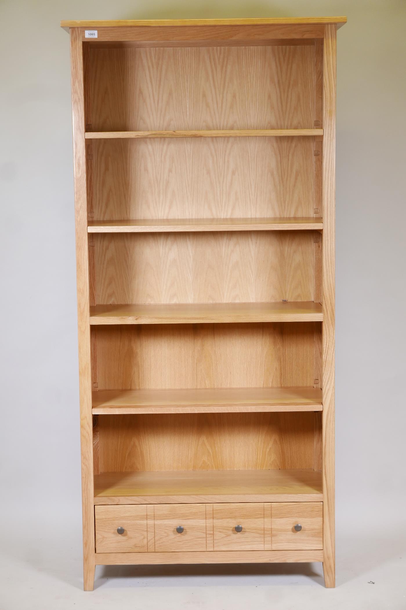 A blonde oak open shelf bookcase, with four shelves and draw to base, supplied by John Lewis, 73"