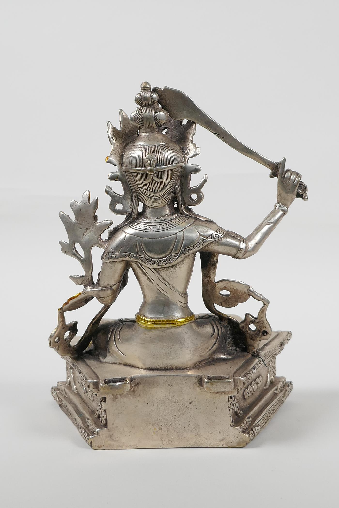 A Sino Tibetan white metal figure of a seated deity carrying a sword with gilt highlights, double - Image 4 of 5