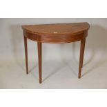 A Regency inlaid mahogany demilune card table with a marquetry top, raised on square tapering